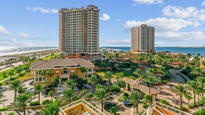 Un hôtel de grande hauteur, avec de nombreux étages, offrant une vue sur la plage et doté d’un jardin bien entretenu agrémenté de palmiers.
