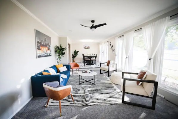 Un salon moderne avec un canapé bleu, un fauteuil blanc et un tapis à rayures.