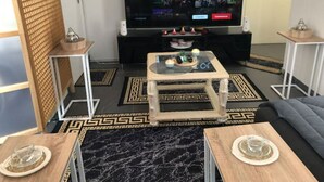 A modern living room with a flat-screen TV, a coffee table, and a sofa.