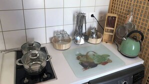 A kitchen with a stove, pots, a kettle, and various utensils.