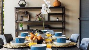 A breakfast table set with blue and white dishes, croissants, and orange juice glasses. - Villa Nueva-Tourist accommodation 3*-Private pool (Saint-Pierre)