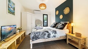 A bedroom with a bed, a TV, a wooden bench, a nightstand, and wall decorations. - Villa Nueva-Tourist accommodation 3*-Private pool (Saint-Pierre)