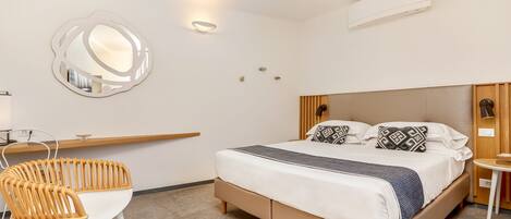 A modern bedroom with a bed, a chair, a bedside table, and a wall-mounted mirror.