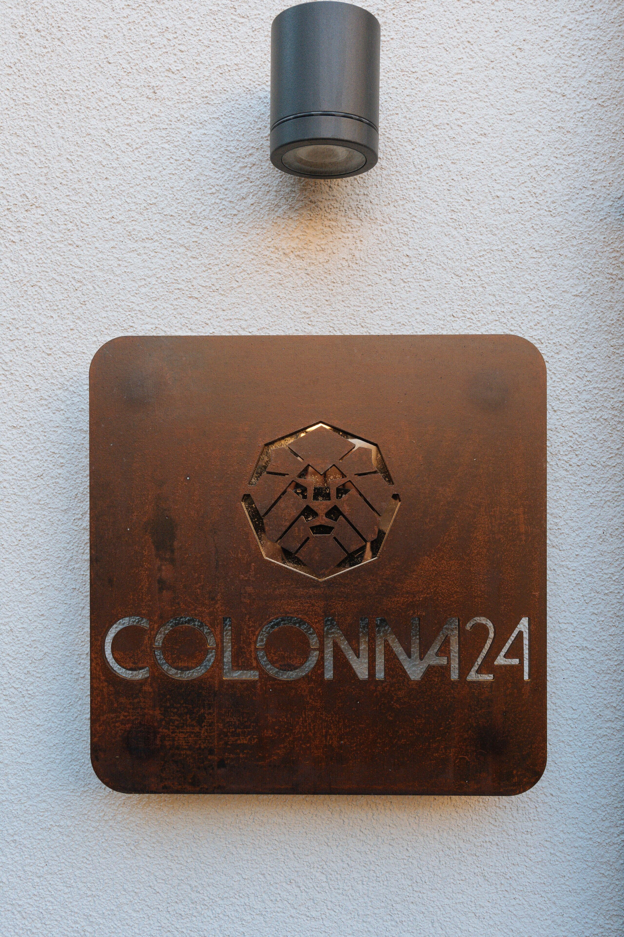 Een metalen plaquette met de tekst 'COLONN24' en een hexagonaal logo.