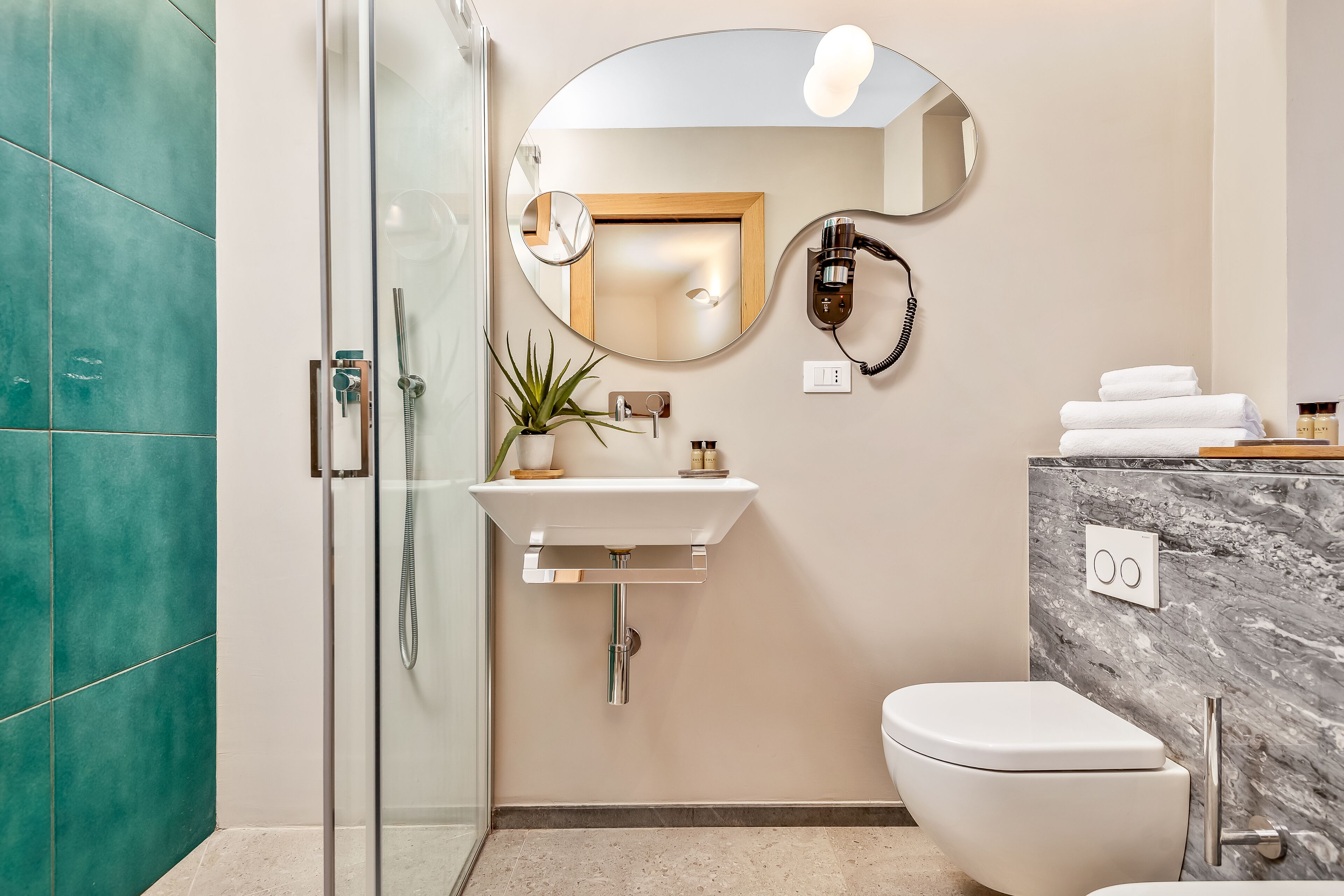 Un baño moderno con cabina de ducha de vidrio, un lavabo con espejo y un inodoro.