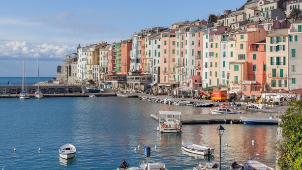 A waterfront with colorful buildings, boats docked along the pier, and a clear sky. - COLONNA24 (Portovenere)