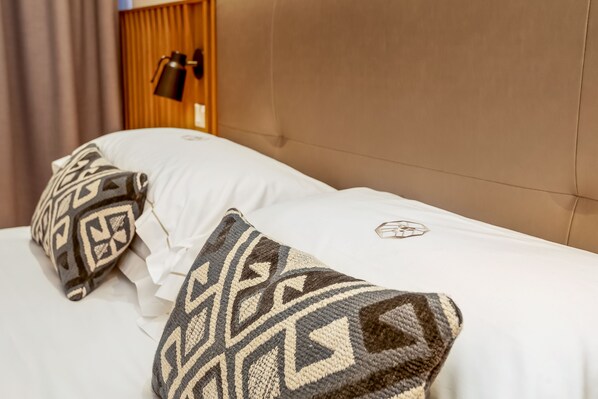 A neatly made bed with patterned pillows and a headboard. - COLONNA24 (Portovenere)