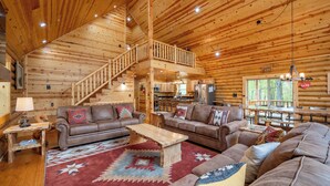 Ein Holzhütten-Interieur mit einer Holztreppe, zwei Sofas, einem Couchtisch und einem Essbereich.