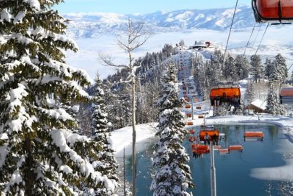Un telesilla con cabinas y un sillón elevador en una zona montañosa nevada.