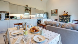 Una cocina acogedora con una mesa de comedor lista para el desayuno, con cruasanes y un periódico.