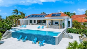 Uma casa moderna com piscina, painéis solares e área de estar externa.