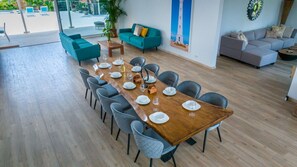 A spacious dining area with a long wooden table set for six, surrounded by grey chairs.
