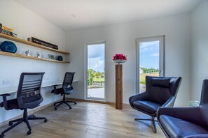 A modern office space with two black office chairs, a wooden floor, and a view through large windows. - Perfect for Groups! 7BR Villa w/ Pool, Ocean Views (Noord)