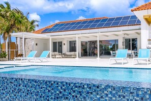 A poolside area with lounge chairs, a covered patio, and a solar panel roof.