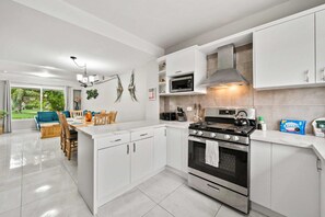A modern kitchen with white cabinets, a stove, microwave, and a dining area with a table and chairs.