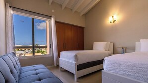 Un dormitorio con dos camas, un sofá, un armario y vistas al exterior.