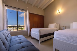 Una camera da letto con due letti, un divano, un armadio e vista sull'esterno.
