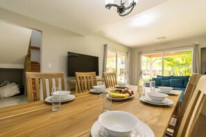 A dining area with a wooden table, chairs, and a television mounted on the wall.