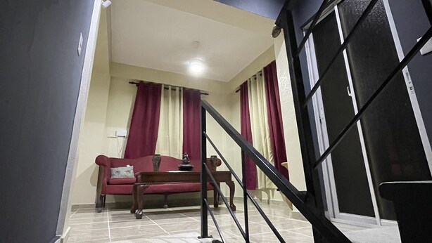 A staircase leading to a living area with a sofa and curtains. - beautiful house in the city (San Francisco de Macorís)