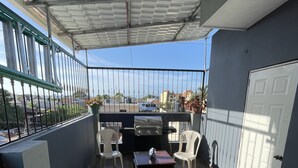 A covered patio area with a grill, seating, and a view of the cityscape. - beautiful house in the city (San Francisco de Macorís)