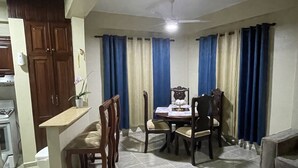 A dining area with a table and chairs, a kitchen area with cabinets, and a ceiling fan. - beautiful house in the city (San Francisco de Macorís)