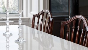 Een eettafel met stoelen, een zwarte lamp en een koelkast in een kamer met een raam.