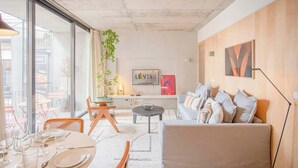 A modern living room with a sofa, coffee table, and dining area. - Liiiving in Porto - Bolhão Trendy Apartment II (Porto)