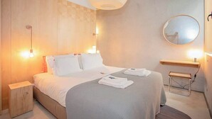 A hotel room with a bed, bedside tables, a mirror, and a hanging light fixture. - Liiiving in Porto - Bolhão Trendy Apartment II (Porto)
