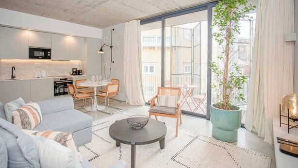A modern living room with a sofa, a coffee table, and a dining area with chairs and a table. - Liiiving in Porto - Bolhão Trendy Apartment II (Porto)