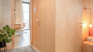 A modern interior with a wooden ceiling, a large sliding door, a dining area with chairs and a table, and a plant. - Liiiving in Porto - Bolhão Trendy Apartment II (Porto)