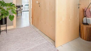 Ein modernes Interieur mit Holzboden, einer großen Holztür, einem runden Seitentisch aus Holz und einem Topfpflanzen.