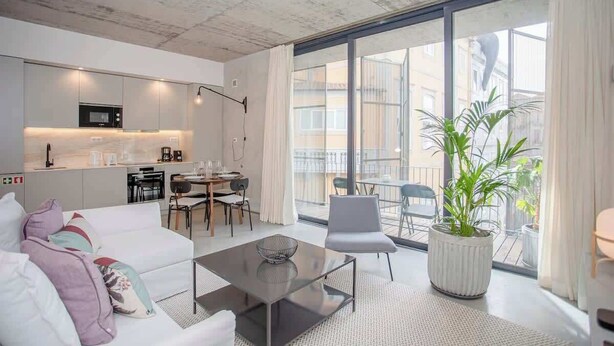 Ein modernes Apartment mit Küche, Essbereich und einem Balkon mit Topfpflanze.