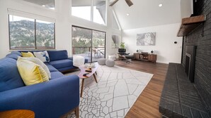 A spacious living room with a blue sofa, a coffee table, and a fireplace. - King & Q beds, views, hot tub, deck, grill (Estes Park)