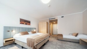 A modern hotel room with a large bed, a smaller bed, a nightstand, a bedside table, and a wall-mounted picture. - Hotel Ehrlich Prague (Prague)