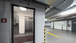 A clean, modern indoor parking area with a visible elevator, fire extinguisher, and clear yellow safety lines on the floor. - Hotel Ehrlich Prague (Prague)