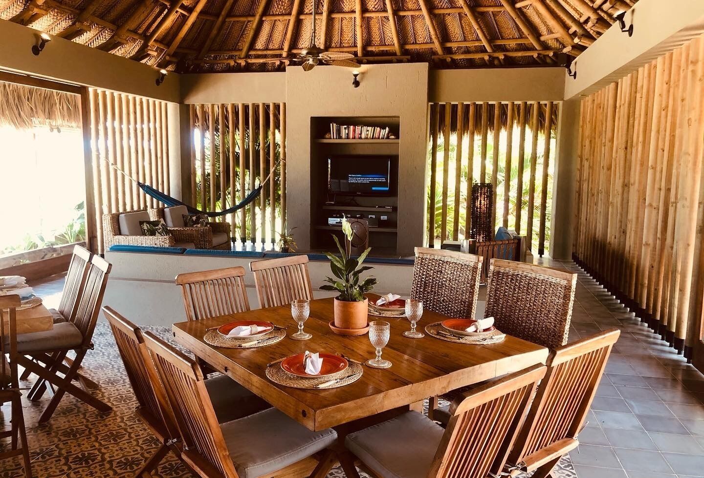 Comedor con mesa de madera dispuesta para cuatro personas, rodeado de sillas de mimbre.
