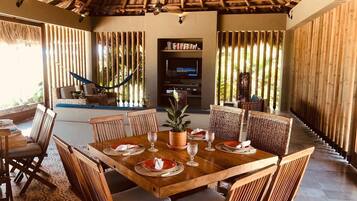 Comedor con mesa de madera dispuesta para cuatro personas, rodeado de sillas de mimbre.
