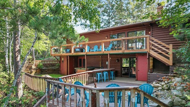 A two-story log cabin with a deck and outdoor seating area. - Family Cabin with hot tub on Cross lake (Crosslake)