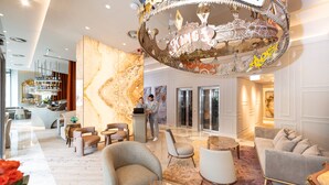A modern lobby with a marble wall, seating area, and a bar. - Dos Reis by The Beautique Hotels (Lisbon)
