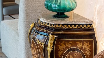 Une petite table d’appoint en bois foncé, agrémentée de détails dorés, et un vase vert.