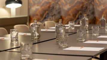 A conference table with clear glass bottles and glasses, a lamp, and a marble wall in the background.