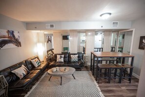 A living room with a sofa, coffee table, and dining area with a table and chairs.
