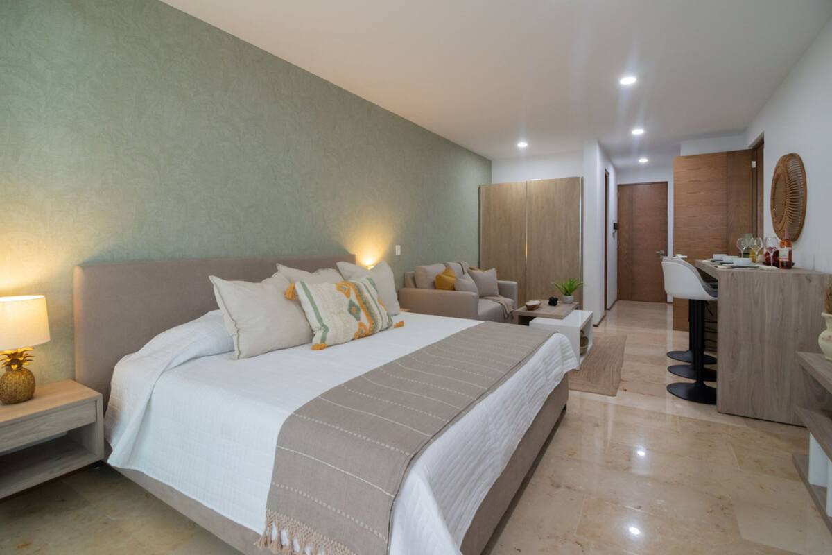 Un dormitorio moderno con una cama grande, mesitas de noche, un escritorio y un armario.
