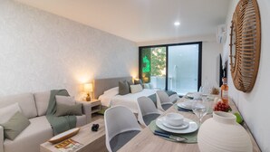 A modern hotel room with a sofa, two single beds, a dining table set for two, and a large vase. - Perfect Place (Playa del Carmen)