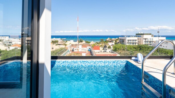 A swimming pool with a view of the ocean and buildings in the background. - Perfect Place (Playa del Carmen)