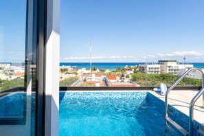 A swimming pool with a view of the ocean and buildings in the background. - Perfect Place (Playa del Carmen)