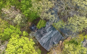 An aerial view of a cabin surrounded by dense forest.