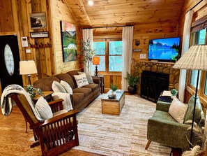 A cozy cabin interior with a wooden interior, a fireplace, a television, and a comfortable seating area.