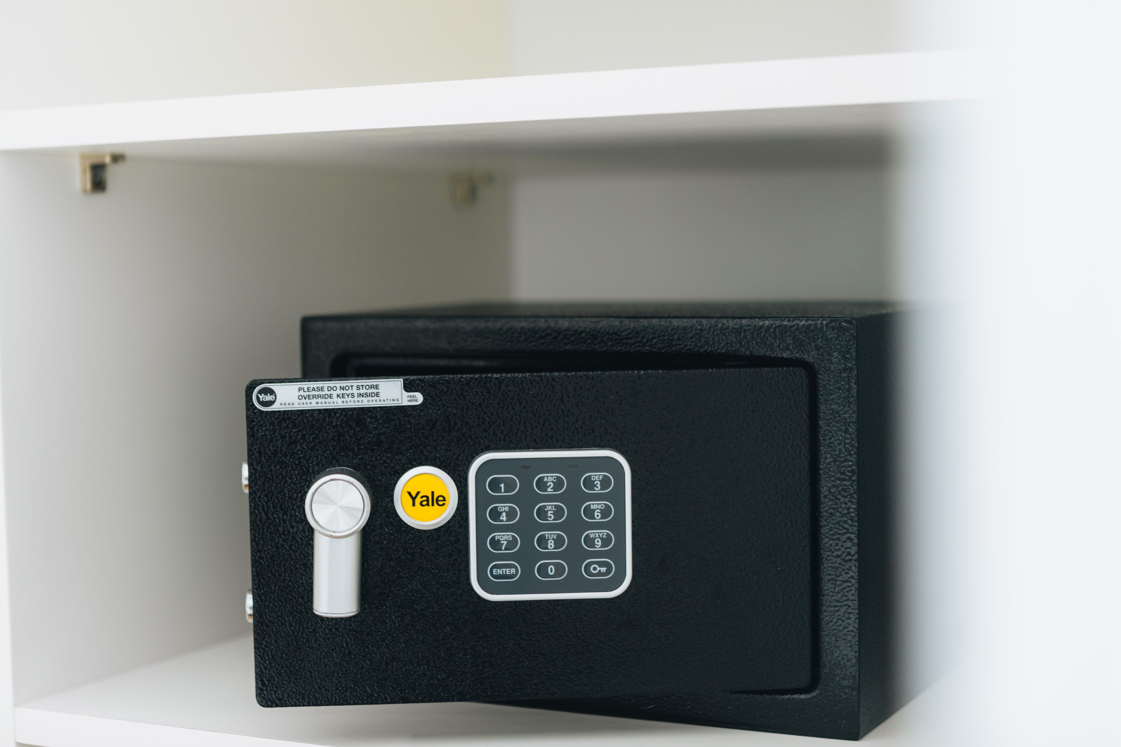 Een kluis van Yale met een combinatiecijferplaat en keypad, geplaatst in een zwarte kluis met een sticker met het Yale logo.
