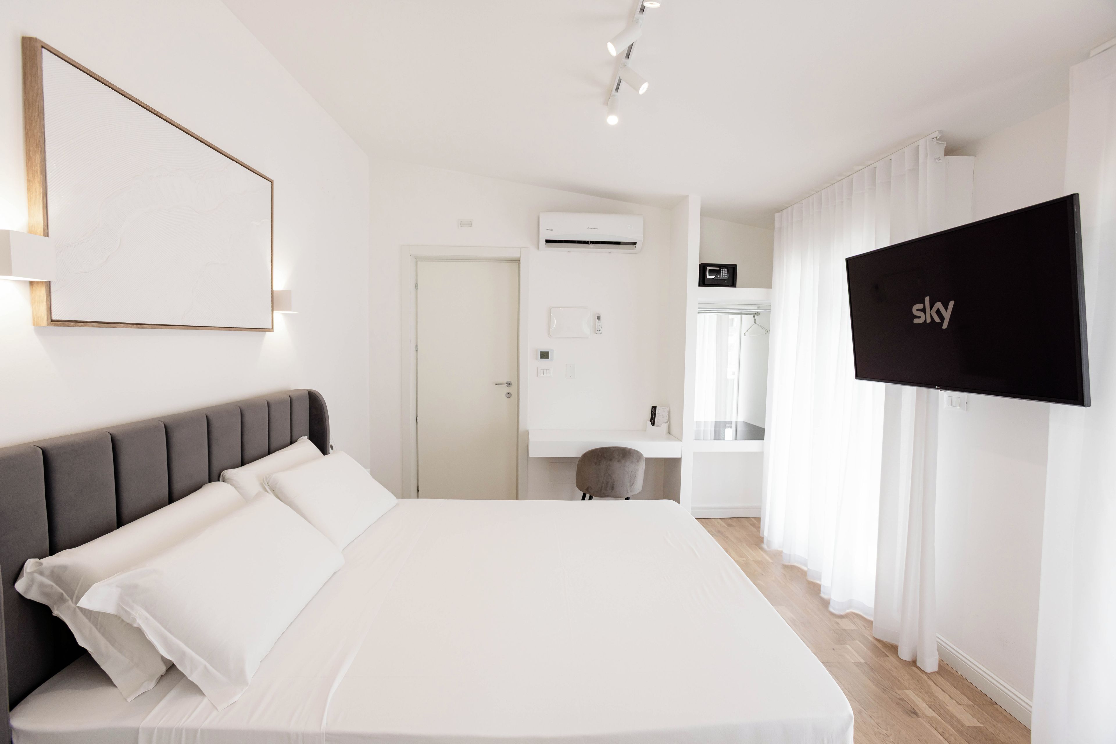 A modern hotel room with a large bed, a flat-screen TV, and a wardrobe.